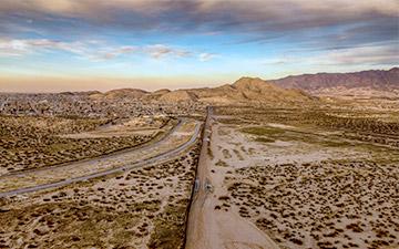 Image of desert land leading up to hills with a country's border running down the middle